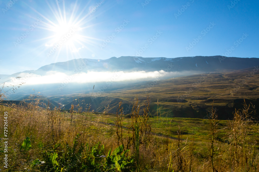 Landscape of foggy mountains and valley under blue sky with sun Landscape of foggy mountains and valley under blue sky with sun