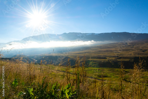Landscape of foggy mountains and valley under blue sky with sun