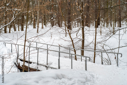 A small metal bridge over a snow-covered river. Countryside in winter.