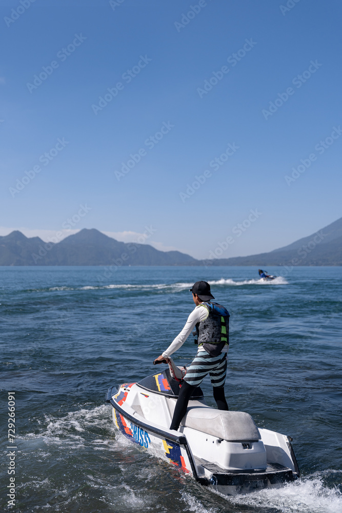 Naklejka premium Two Young Hispanic Men Riding Jet-Skis in Atitlan Lake, Guatemala