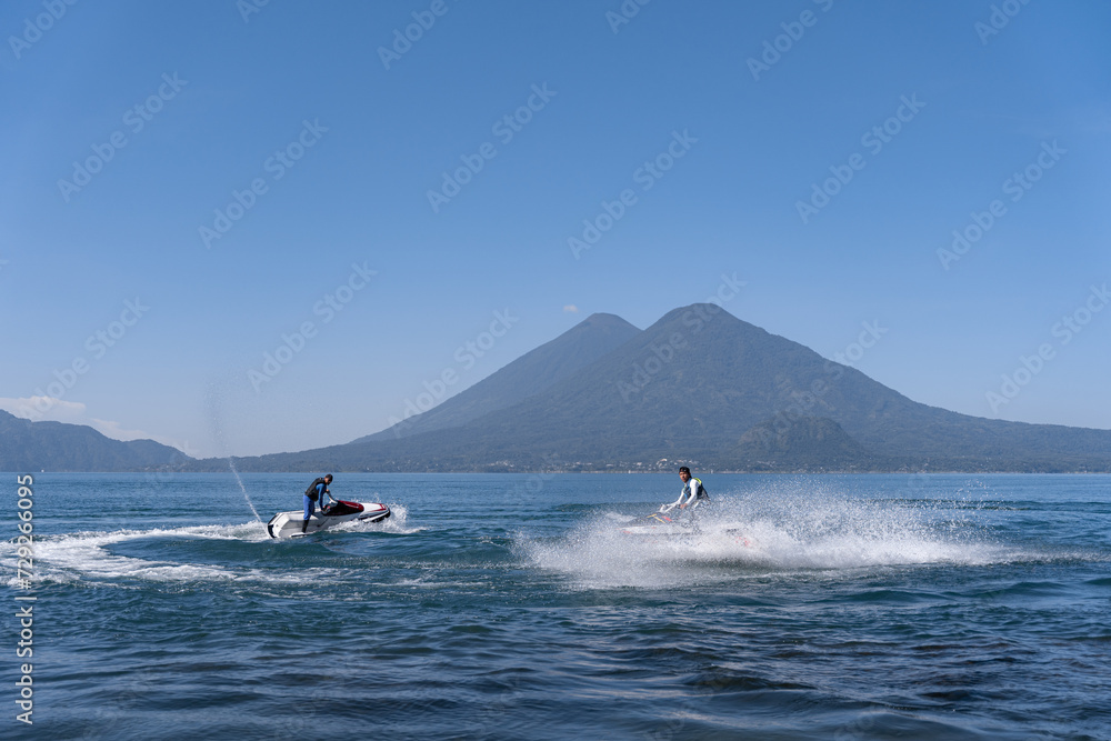Fototapeta premium Two Young Hispanic Men Drifting Water with Jet-Skis in Atitlan Lake, Guatemala