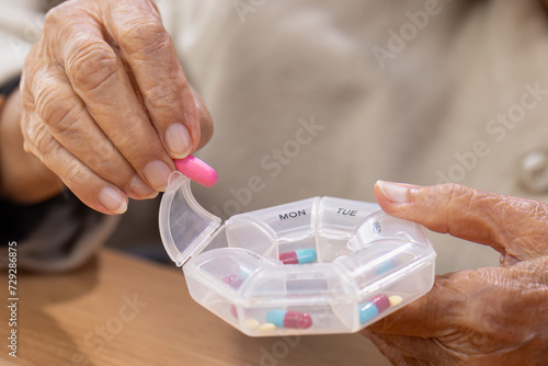 Foto Elderly woman putting pills into pill box for the week.