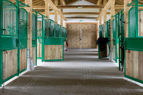 Long empty corridor in modern stable building. Horse stalls boxes on both sides.