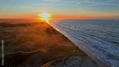 Panoramiv view The beach is washed by sea waves, high dunes have formed, the summer house standing on the dunes is surrounded by a mystical mist, and the sun is setting on a winter evening. photo