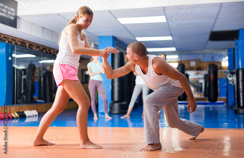 Young woman doing wristlock movement during group self protection training.