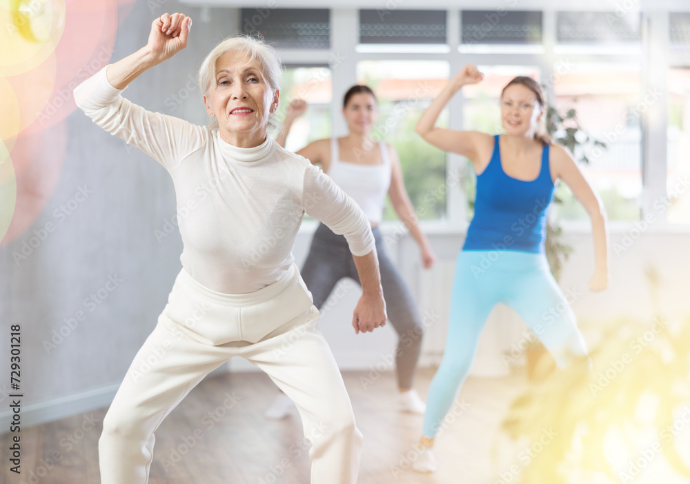 Fototapeta premium Happy women practicing aerobics in light fitness studio during workout session