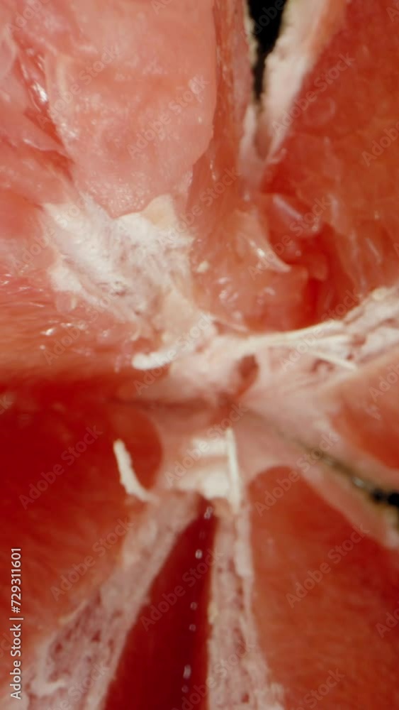 Vertical video. Top View of a Falling and Rotating Grapefruit on a Black Background, Broken into Pieces. Vertical video. Top View of a Falling and Rotating Grapefruit on a Black Background, Broken into Pieces.