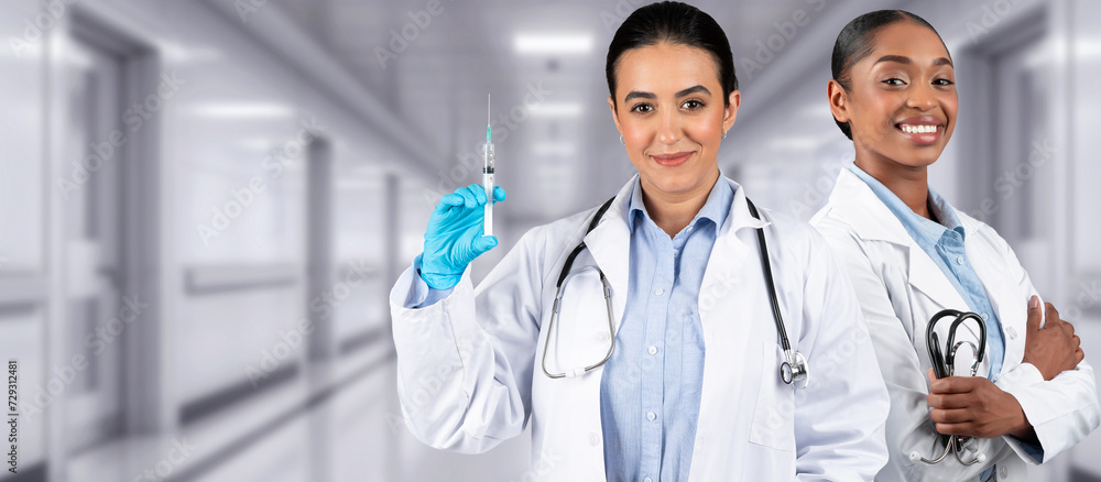 Two women healthcare professionals in a clinical setting, one holding a syringe Two women healthcare professionals in a clinical setting, one holding a syringe