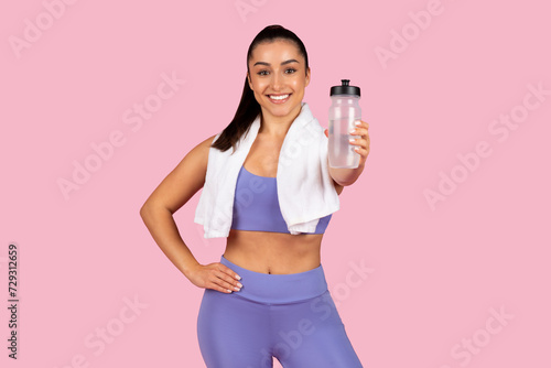 Active woman with water bottle and towel after workout