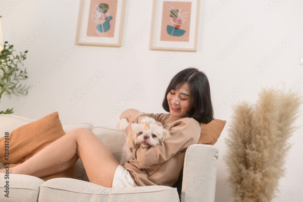 Happy young asian woman cuddling and spending time with cute dog in living room. Happy young asian woman cuddling and spending time with cute dog in living room.