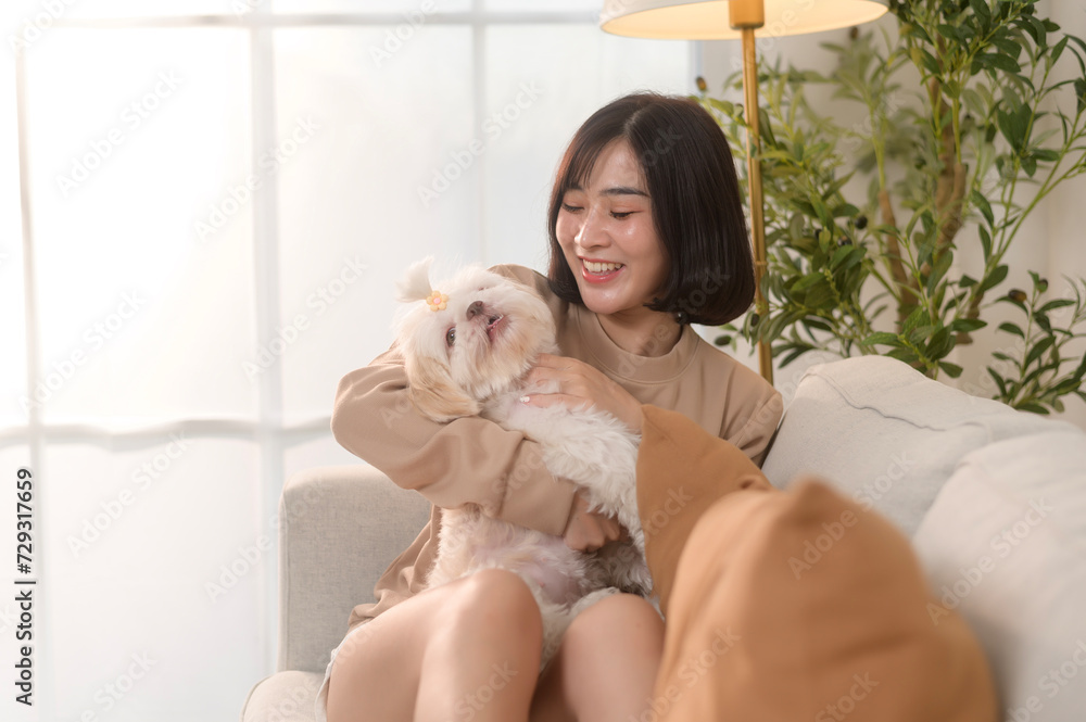 Happy young asian woman cuddling and spending time with cute dog in living room. Happy young asian woman cuddling and spending time with cute dog in living room.