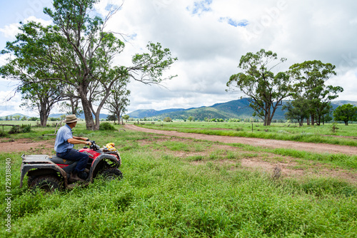 farmer on four wheeler riding through farm paddock
