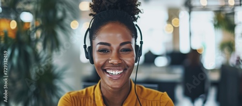 A Black call centre agent, young and laughing while on a call with a headset. photo