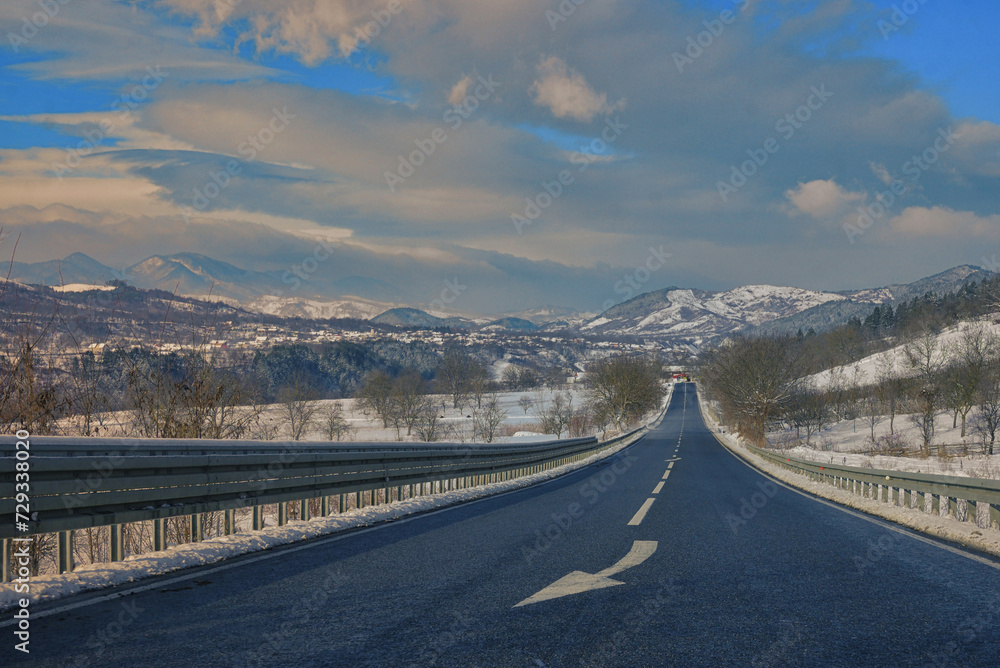 Obraz premium Winter scene of a road and mountains in rural area