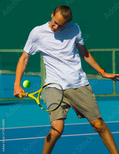 Tennis player playing tennis on a hard court on a bright sunny day