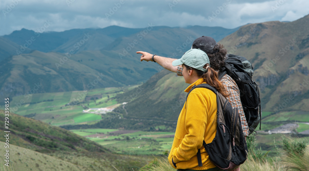 Young Latin American couple with backpacks exploring in the middle of the wilderness on a mountain
