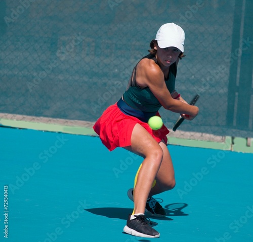 A girl plays tennis on a court with a hard blue surface on a summer sunny day   © Павел Мещеряков