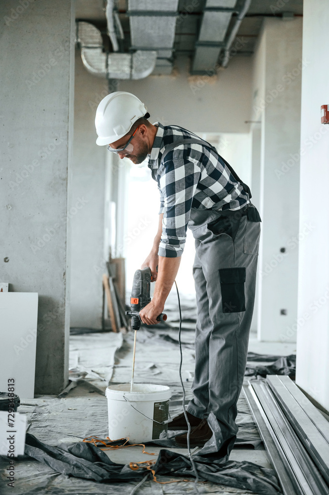 Mixing the concrete. Repairman in uniform is in the unfinished building Mixing the concrete. Repairman in uniform is in the unfinished building