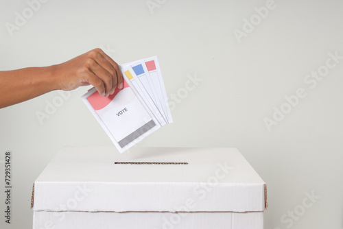 Close up of hand inserting and putting the voting paper into the ballot box. General elections or Pemilu for the president and government of Indonesia. Isolated image on white background photo