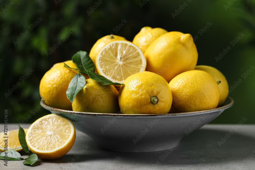 Fresh lemons and green leaves on grey table outdoors, closeup Fresh lemons and green leaves on grey table outdoors, closeup