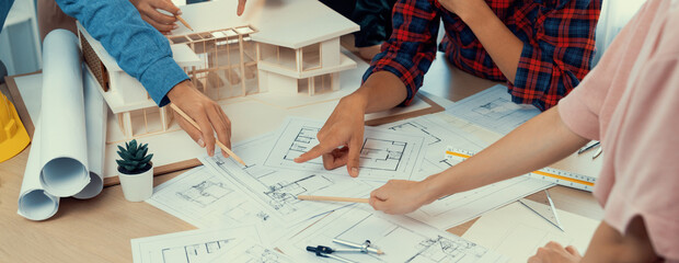 Skilled architect engineer team meeting pointing at blueprint while professional interior designer analysis and brainstorming about house structure. Creative design and teamwork concept. Burgeoning.