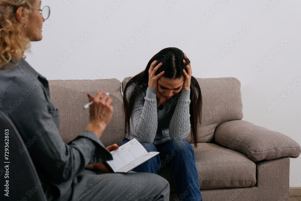 Fototapeta premium Therapy session concept. Young woman getting a professional help from an adult female psychiatrist in her office. Close up, copy space, background.