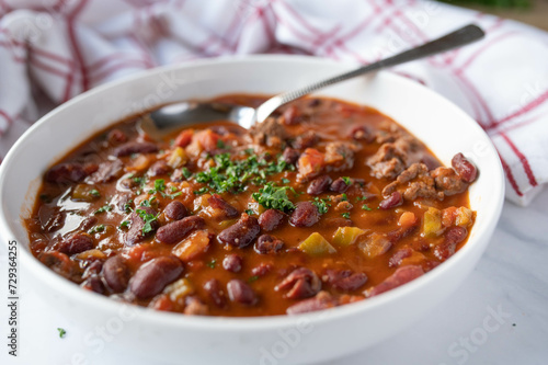 Low fat bean soup or bean stew mexican style with kidneybeans, lean ground beef, and vegetables on plate isolated on light background.