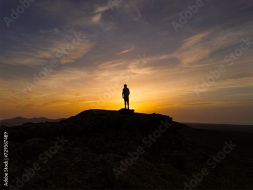 Spectacular sun set image over Volcan Calderon Hondo volcanic crater with silhouetted figure against the setting sun and skyscape near Corralejo, Fuerteventura, Canary Islands, Spain