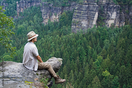 Mann sitzt auf Felsen und schaut in die Ferne, Elbsandsteingebirge, Sachsen, Deutschland
