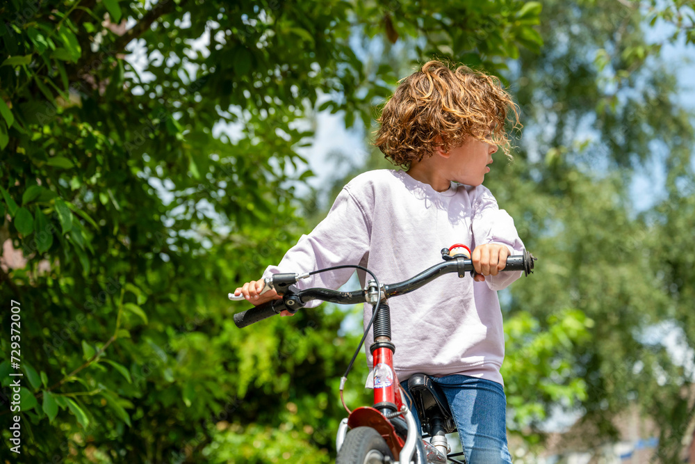 Young boy on his bike looking back Young boy on his bike looking back