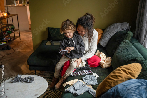 Mother sitting with son and showing him her pregnancy scan photo