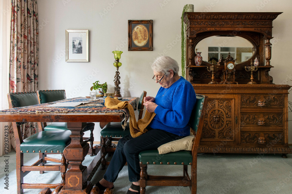 Elderley lady knitting at her dining room table Elderley lady knitting at her dining room table
