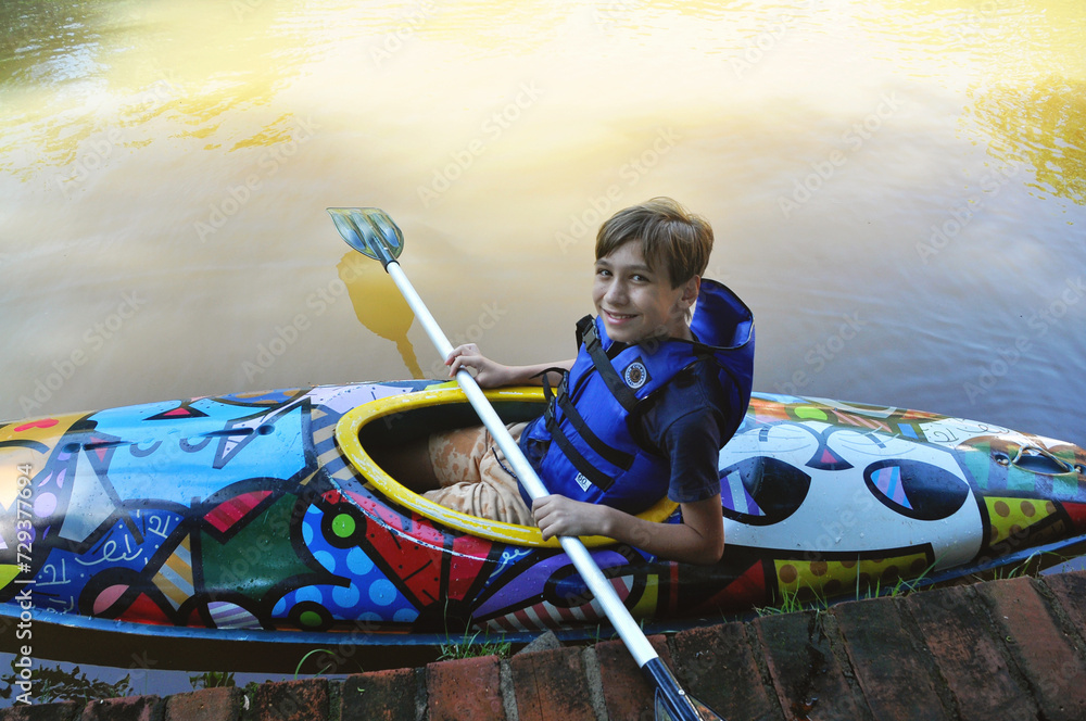 Obraz premium garoto praticando canoagem com canoa no lago, férias escolares 