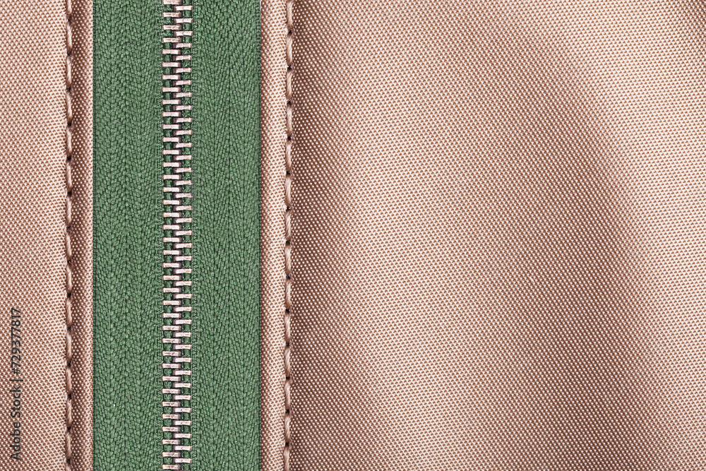 Brown beige fabric green metal zipper. Vibrant color style clothing accessories. Sewer element background. Closed zipped zipper. Silver gray shiny zipper teeth background. Empty copy space fabric. Brown beige fabric green metal zipper. Vibrant color style clothing accessories. Sewer element background. Closed zipped zipper. Silver gray shiny zipper teeth background. Empty copy space fabric.
