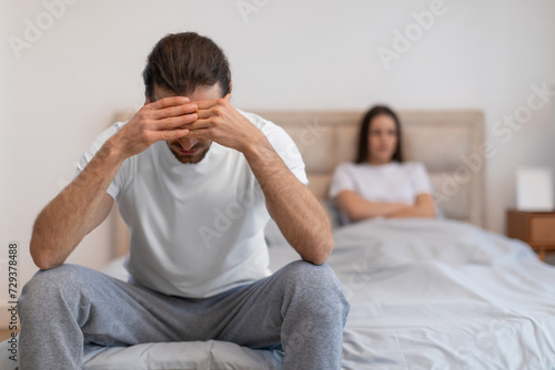 Stressed man with hands on head, woman in background