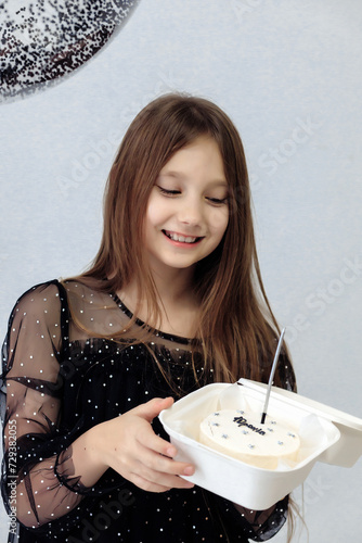 A little girl celebrates her 10th birthday. A girl on a white background in a black dress with long straight hair. Party, holiday