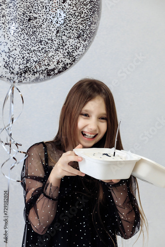 A little girl celebrates her 10th birthday. A girl on a white background in a black dress with long straight hair. Party, holiday