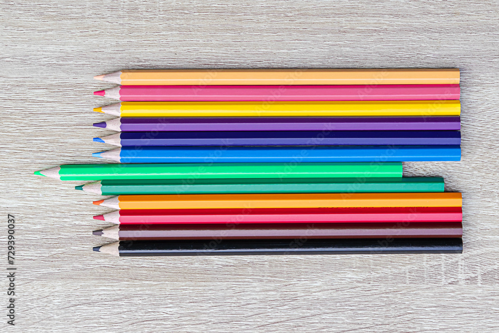 Group of color pencil laying in row straight line on wooden table background. Color pencils and copy space. Education concept. Group of color pencil laying in row straight line on wooden table background. Color pencils and copy space. Education concept.