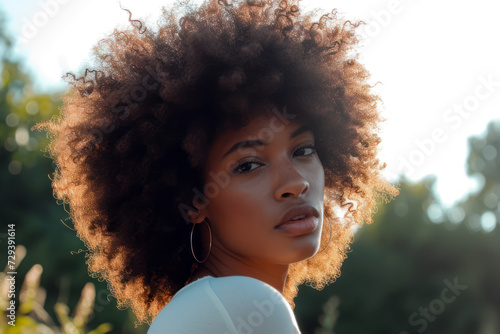 African girl with curly hair in a light sweatshirt on a blurred background