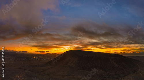 Spectacular sun set image over Volcan Calderon Hondo volcanic crater silhouetted against the setting sun and skyscape near Corralejo, Fuerteventura, Canary Islands, Spain