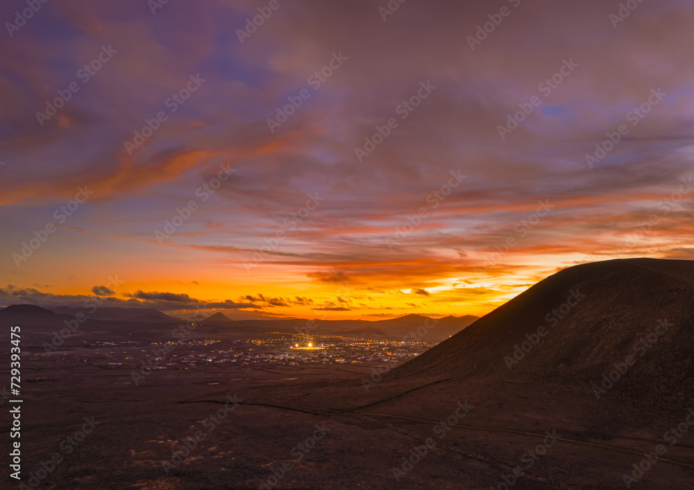Spectacular sun set image over Volcan Calderon Hondo volcanic crater silhouetted against the setting sun and skyscape near Corralejo, Fuerteventura, Canary Islands, Spain Spectacular sun set image over Volcan Calderon Hondo volcanic crater silhouetted against the setting sun and skyscape near Corralejo, Fuerteventura, Canary Islands, Spain
