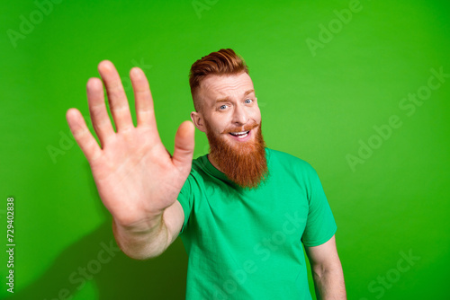 Portrait of cheerful guy with long red beard wear stylish t-shirt showing palm give you highfive isolated on green color background