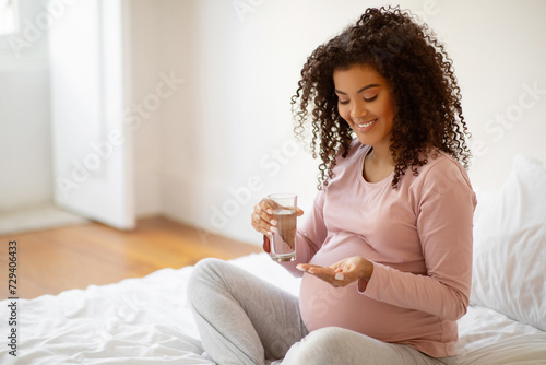 Prenatal Vitamins. Smiling Black Pregnant Woman Holding Pills And Glass Of Water,