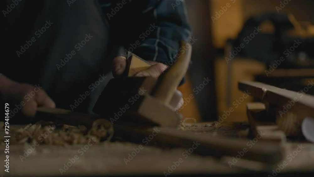 Confidently using the tool of a wood plane, planing wood, a skilled worker exhibits the concept of a talented craftsman in industry. Working at a carpenter's table in a workshop Confidently using the tool of a wood plane, planing wood, a skilled worker exhibits the concept of a talented craftsman in industry. Working at a carpenter's table in a workshop