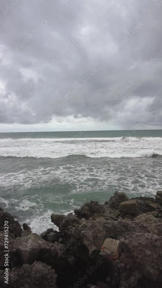 Beautiful vertical video of beachside views, natural panoramas, sea water accompanied by crashing waves and coral rocks with cloudy skies in the afternoon, on Karang Paranje beach, Garut Beautiful vertical video of beachside views, natural panoramas, sea water accompanied by crashing waves and coral rocks with cloudy skies in the afternoon, on Karang Paranje beach, Garut