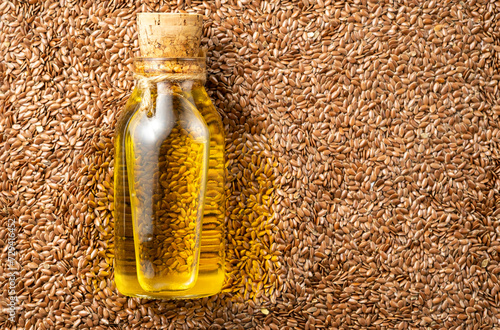 A bottle of vegetable oil lies on flax seeds, a super food rich in vitamins and omega-3 fats.