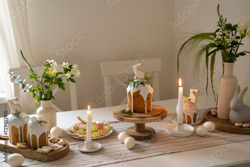The dining room is decorated for Easter with candles and flowers. Traditional bread kulich, rabbit cookies and eggs.