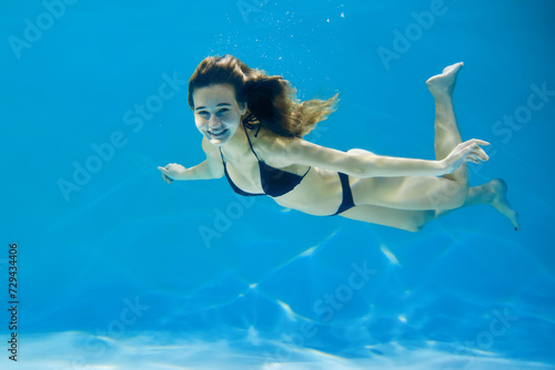 A young woman in a swimsuit swims in the pool. Creative concept