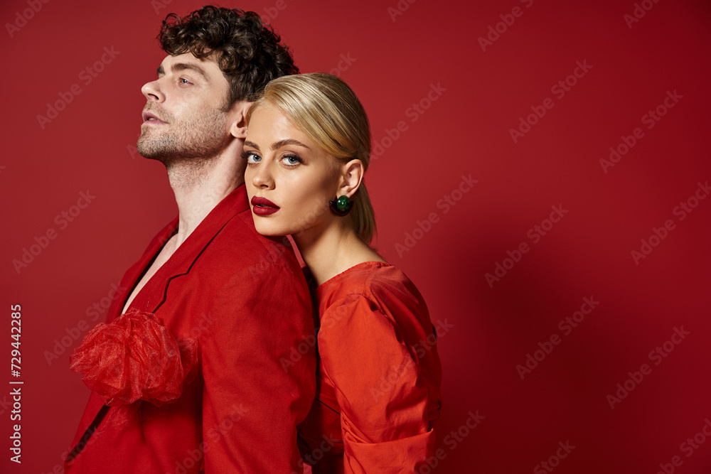 blonde woman with red lips leaning on shoulder of man in vibrant attire of red background, fashion blonde woman with red lips leaning on shoulder of man in vibrant attire of red background, fashion