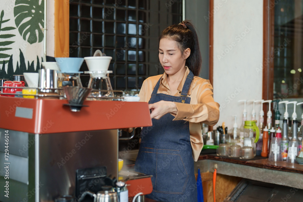 Asian woman shop owner, machine with finely ground coffee is being introduced coffee machine, hold coffee use hot coffee mug support brewing coffee, before making menu according customer's order. Asian woman shop owner, machine with finely ground coffee is being introduced coffee machine, hold coffee use hot coffee mug support brewing coffee, before making menu according customer's order.